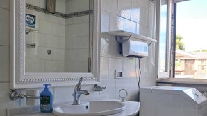 A bathroom with a white sink, a mirror, a towel rack, and a window.