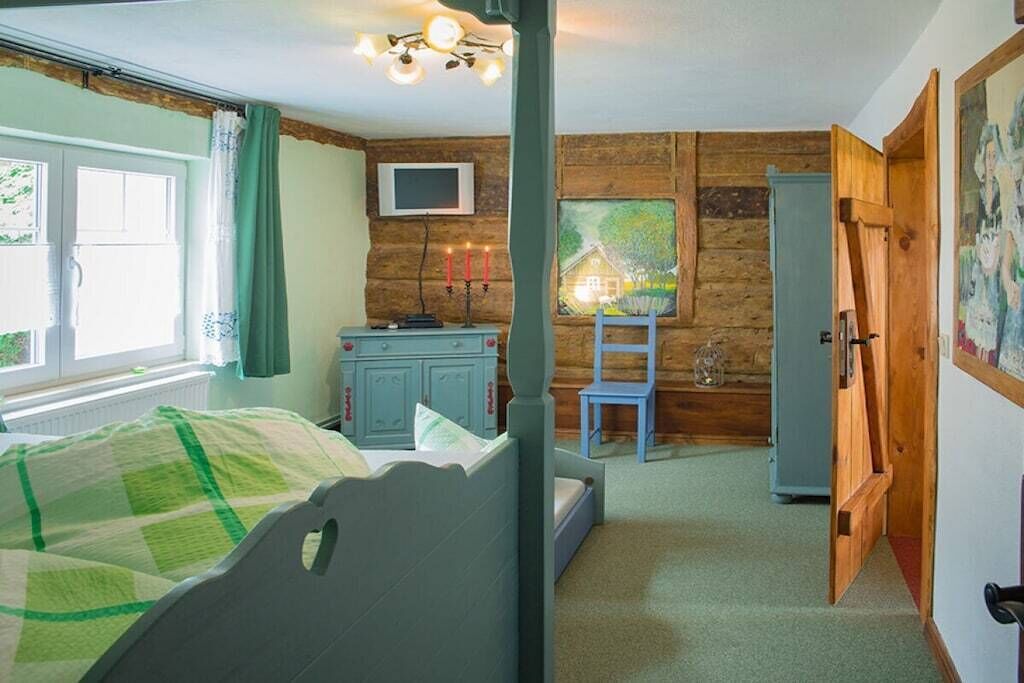 Un dormitorio con cama, cómoda, televisor y un cuadro en la pared.