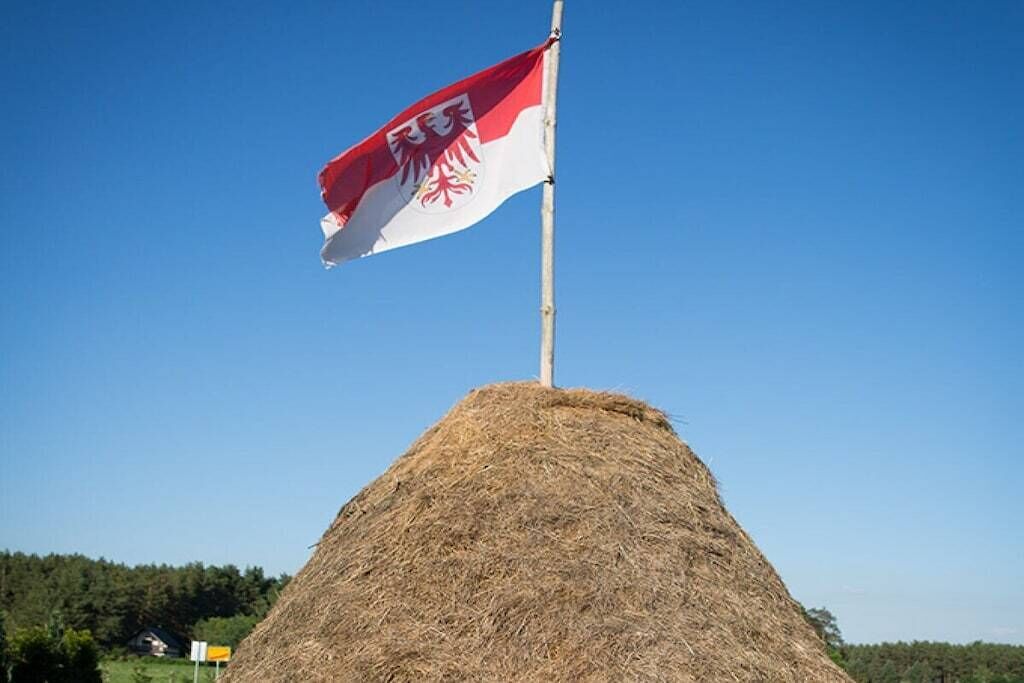 Een vlag op een vlaggenmast, met een grasheuvel op de voorgrond.