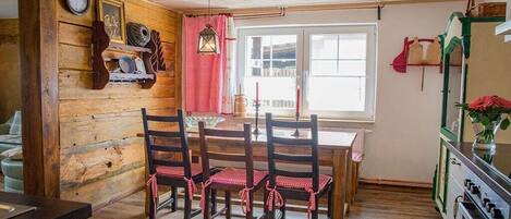 Un interior de madera con una mesa de comedor, sillas, un reloj y un ventanal.