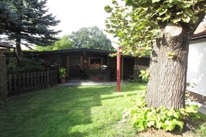 Un patio trasero con cerca de madera, un árbol y un edificio con una puerta.