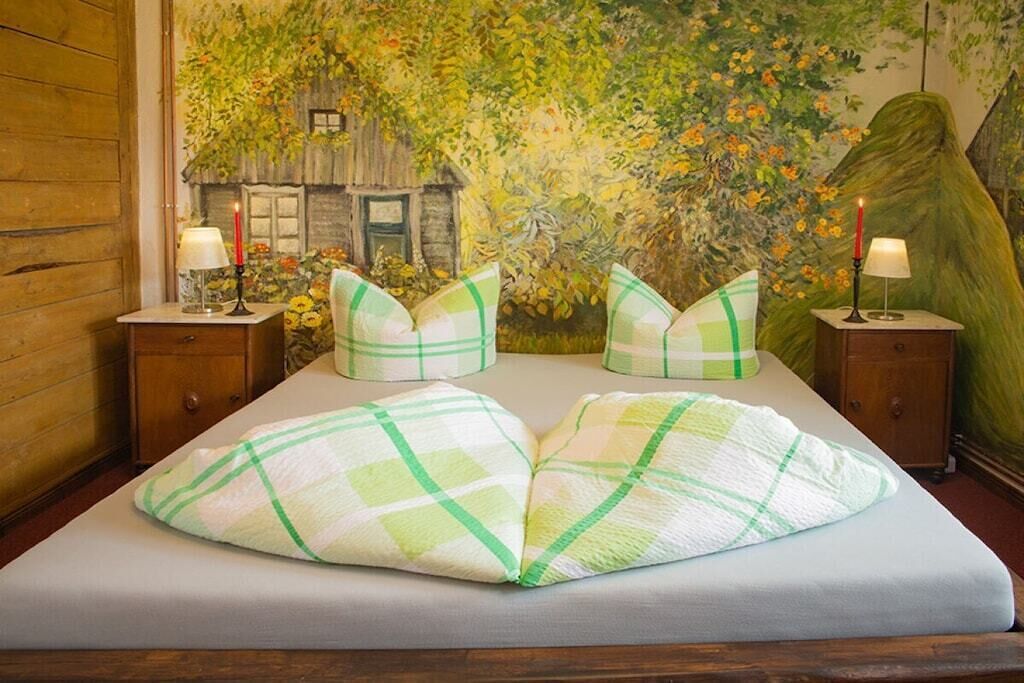A bed with a checkered pillow and a wall mural.