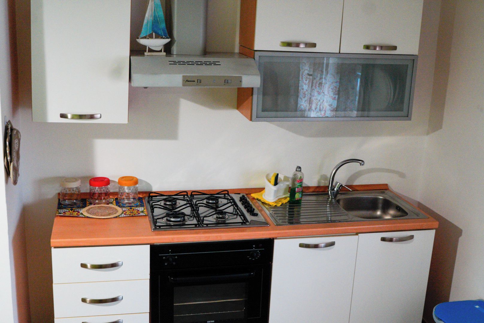 A compact kitchen with a gas stove, a built-in oven, a sink, and a microwave.