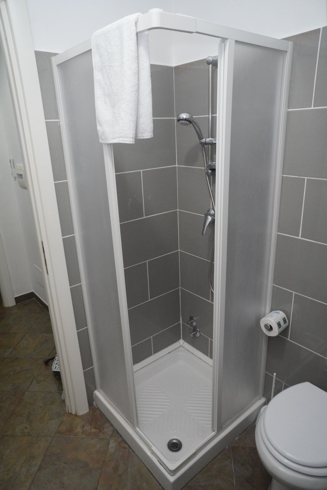 A shower enclosure with a white showerhead and a handheld shower attachment.