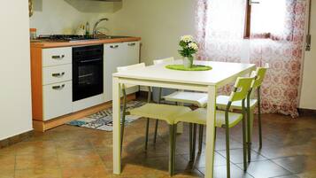 A kitchen with a white table and chairs, a stove, and a sink.