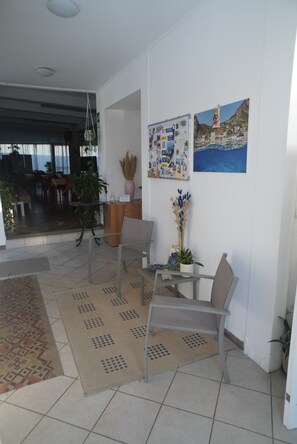 A modern living room with a dining area, a bulletin board, and a painting of a coastal scene.