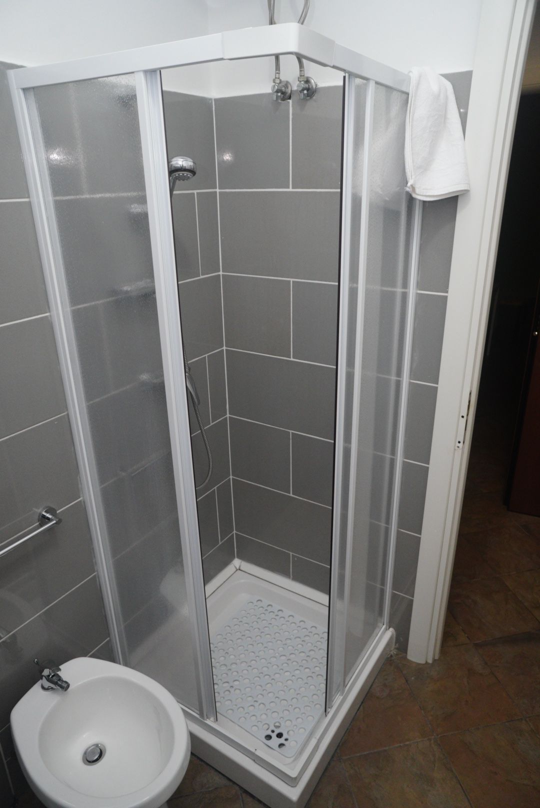 A walk-in shower with a glass door, a white sink, and a towel hanging on the door.