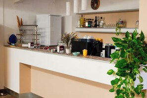 A kitchen counter with various items including a coffee machine, a plant, and kitchen appliances.