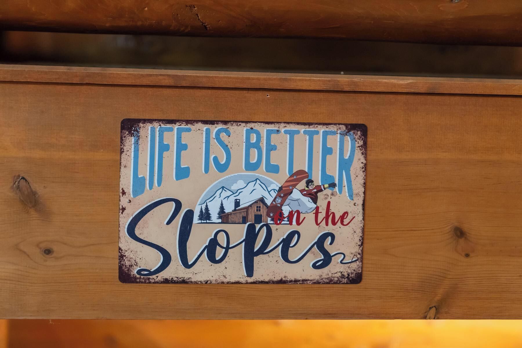 Une pancarte en bois portant l’inscription : « La vie est plus belle sur les pistes ».