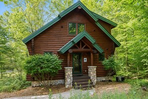 Eine Blockhütte mit Steinunterbau, einer Veranda und einem grünen Dach.
