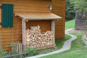 Eine Holzhütte mit einem Holzstapel davor.