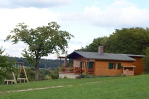 Eine Holzhütte mit Veranda, Schaukel und Kamin.