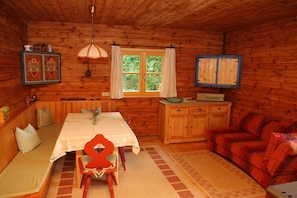 A cozy cabin interior with a dining table, bench seating, a sofa, and a window with curtains. - Holiday apartment with 2 bedrooms (Leutenbach)