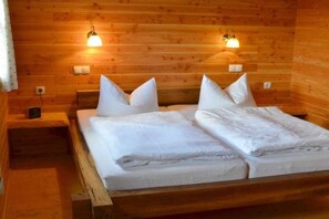 Una camera arredata in stile chalet con un letto matrimoniale, due lampade a parete e un comodino.