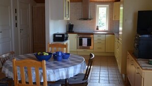 A compact kitchen with a dining table, chairs, and basic appliances.