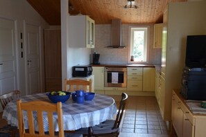 A compact kitchen with a dining table, chairs, and basic appliances.