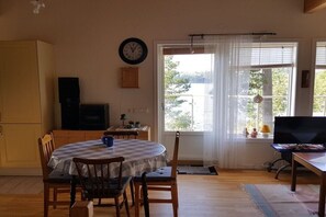 Ein Essbereich mit einem runden Tisch, Stühlen, einer Wanduhr und einem Fenster mit Blick nach draußen.