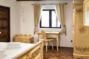 A room with a bed, a wooden desk, a chair, a wardrobe, and a window with curtains.