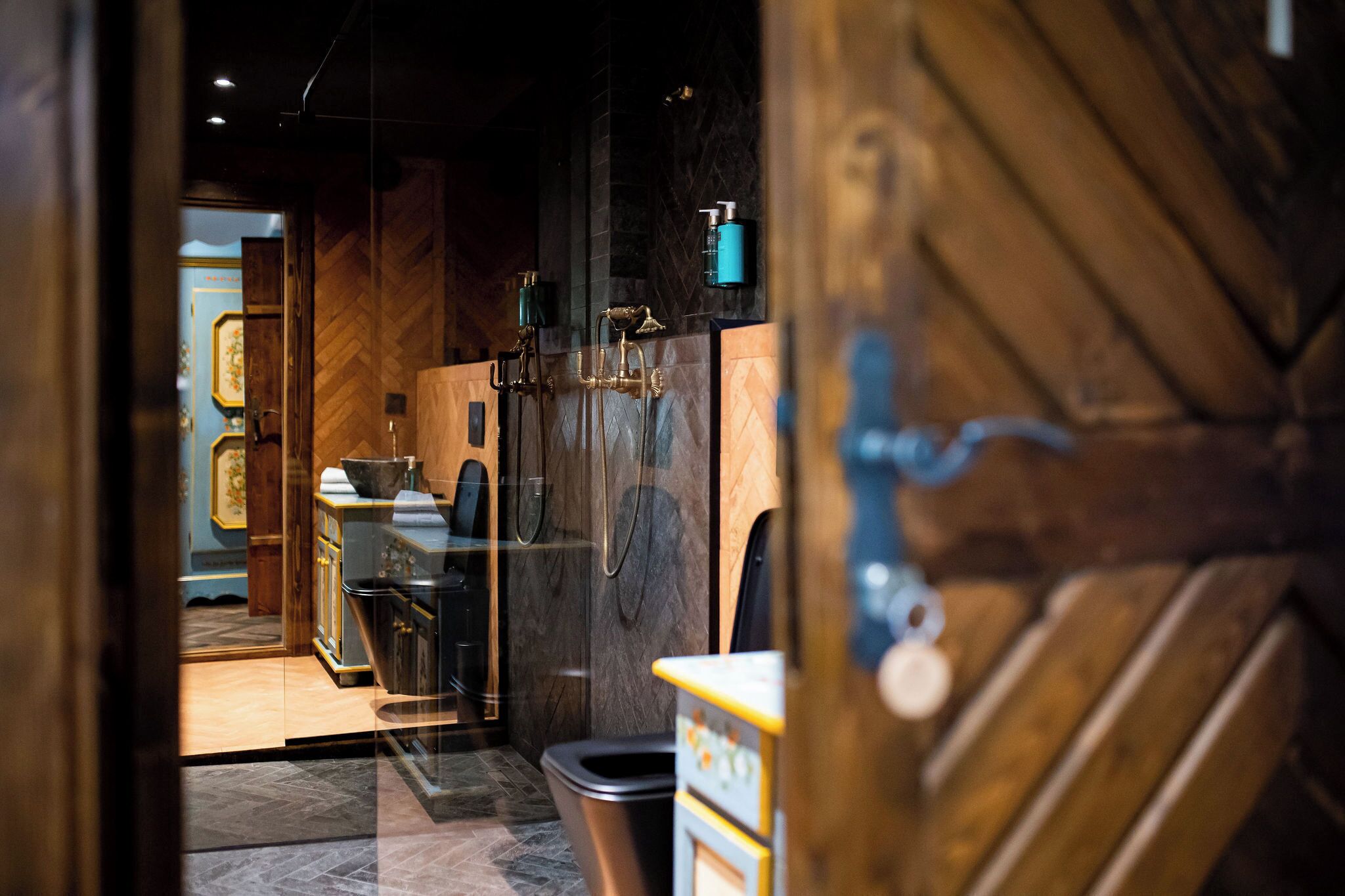A modern bathroom with a glass partition, a shower with a vintage faucet, and a wooden door.