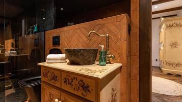 Un tocador de baño con lavabo de piedra, grifo y dispensador de jabón.