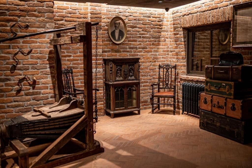 A room with a brick wall, a wooden cabinet, a chair, and vintage suitcases.