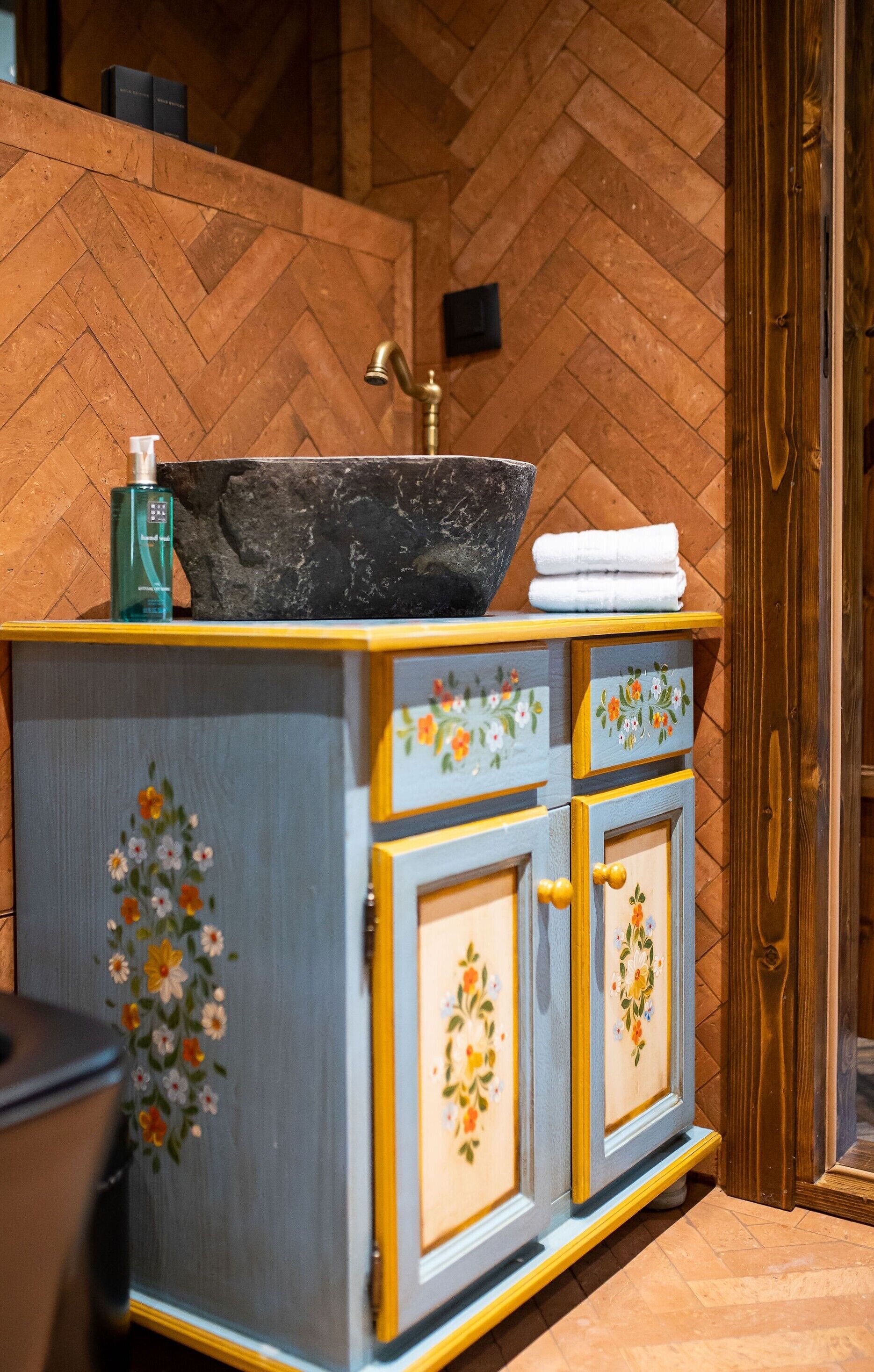 A bathroom vanity with a stone basin, a bottle of hand soap, and a towel.