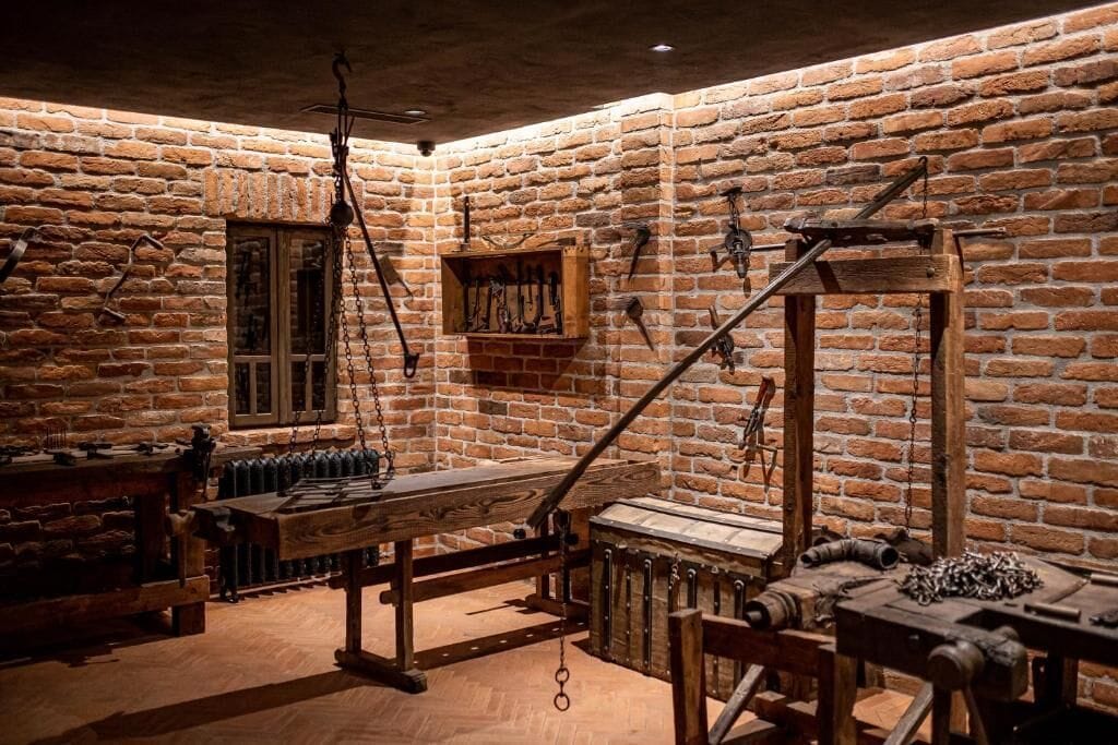 Una habitación rústica con paredes de ladrillo visto, una mesa de madera y diversas herramientas.