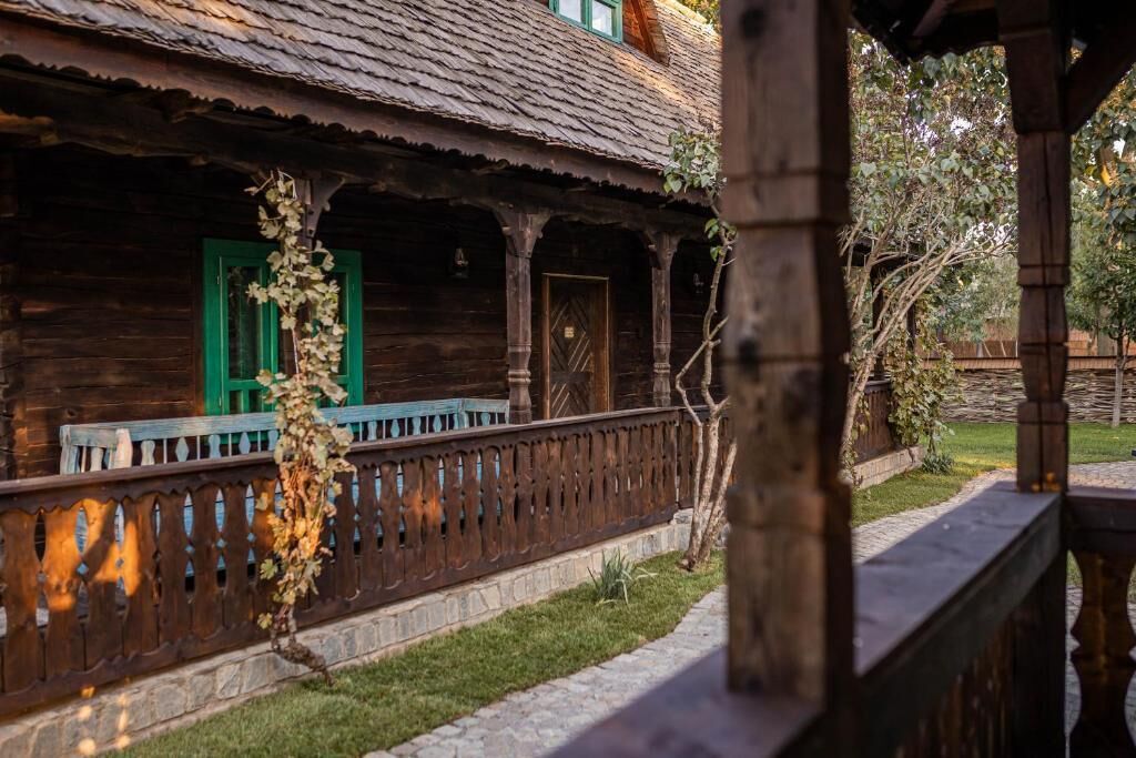 Un edificio rústico de madera con un porche, contraventanas verdes y un camino de piedra.
