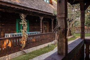 A rustic wooden building with a porch, green shutters, and a stone pathway.
