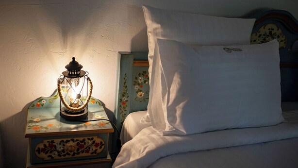A bed with white bedding, a white pillow, and a decorative lantern on a nightstand.
