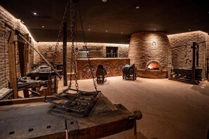 A historical setting with a stone fireplace, wooden furniture, and a hanging chain mechanism. - Gradina Snagov (Sat Snagov, Comuna Snagov)