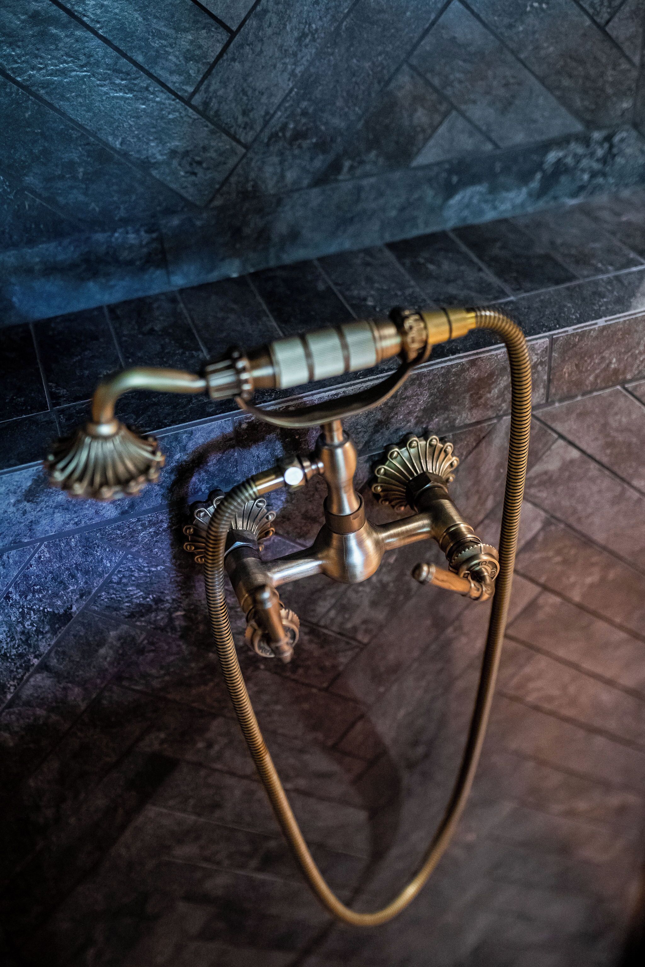 Um acessório de banho em metal dourado, com duas duchas e uma mangueira flexível.