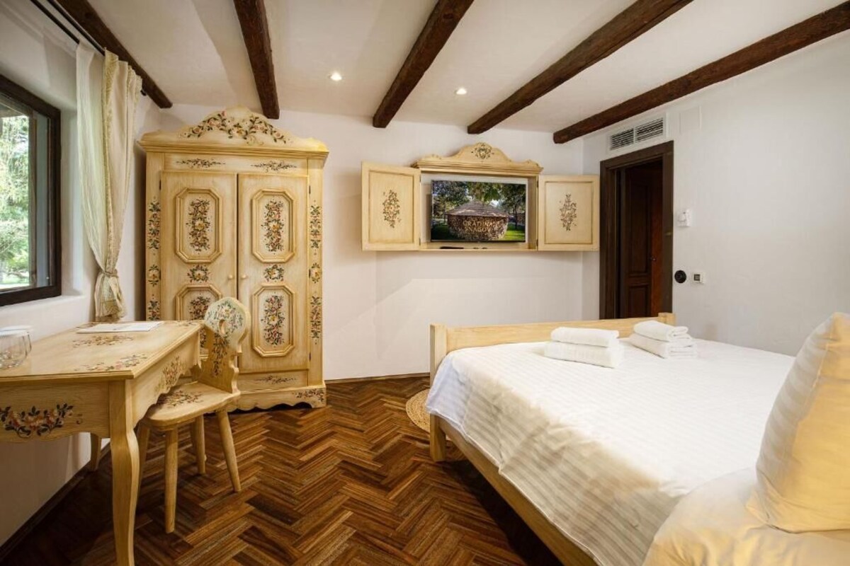A bedroom with a wooden bed, a desk with a chair, and a wardrobe.