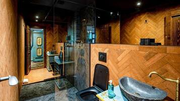 Un baño moderno con pared de madera estampada en espiga, un lavamanos de piedra y zona de ducha con mampara de vidrio.