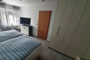 A bedroom with a bed, a television, a wardrobe, and a door. - Holiday home with 1 bedroom (Dornumersiel)
