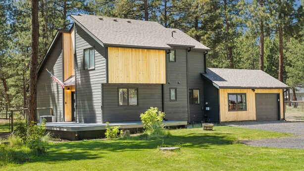A modern two-story house with a sloped roof, a front porch, and a garage. - Modern Tollgate Mountain Retreat (Sisters)