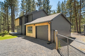A two-story house with a garage, surrounded by trees.