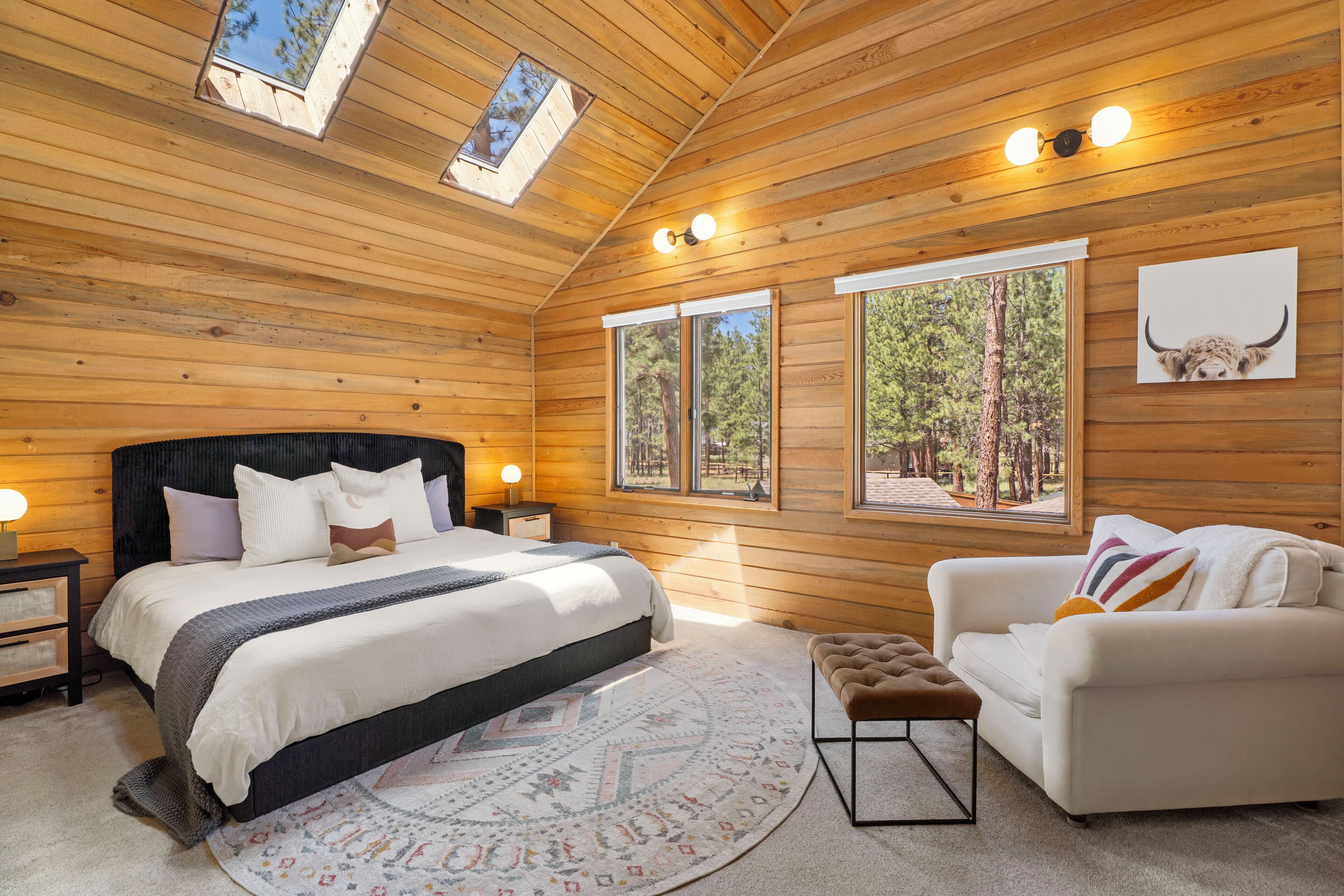 A log cabin bedroom with a bed, bedside tables, a sofa, and a rug.