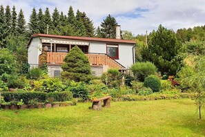 A house with a wooden deck, surrounded by a lush garden and tall trees. - Small country estate (Steinbach-Hallenberg)