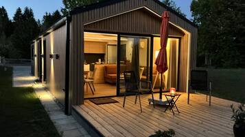 A modern outdoor living space with a deck, seating, and a glass door leading to an interior area.