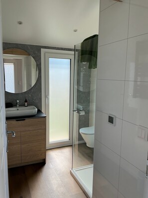 A modern bathroom with a glass shower enclosure, a toilet, and a sink with a mirror. - Tiny Home "Auszeit" with Mountain View, Wi-Fi, and Air Conditioning (Scheidegg)