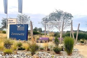A sign for Zinnowitz with a welcoming message, surrounded by a landscaped area with rocks, plants, and wooden structures. - Apartment 1 - Strandperle (Zinnowitz)