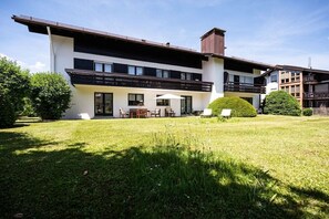 Un edificio moderno a due piani con tetto piatto, ampie finestre e un prato curato.
