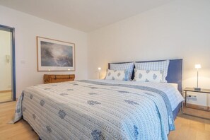 Una camera da letto con un letto grande, un comodino, una lampada e un quadro appeso al muro.