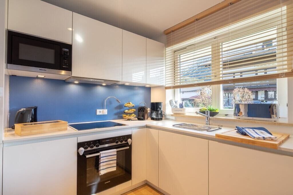 Una cocina moderna con armarios blancos, un microondas negro, una estufa y un lavamanos.