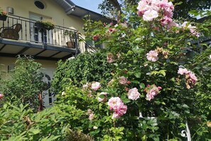 Een tuin met bloeiende roze bloemen en een balkon met een hekwerk.