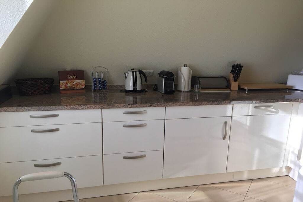Een keuken met witte kastjes, een waterkoker, een broodrooster en een doos met lekkernijen.