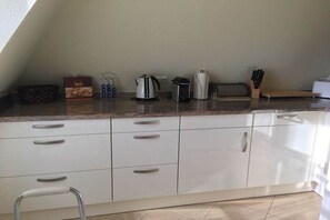 Ett kök med vita skåp, en vattenkokare, en brödrost och en låda med snacks.
