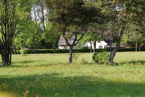 Un champ verdoyant avec des arbres et un bâtiment blanc doté d’un toit rouge.