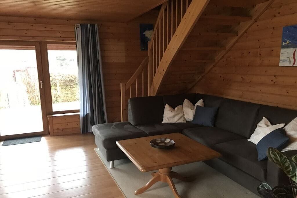 Ein Holzinnenraum mit einer Couch, einem kleinen Tisch und einer Treppe.